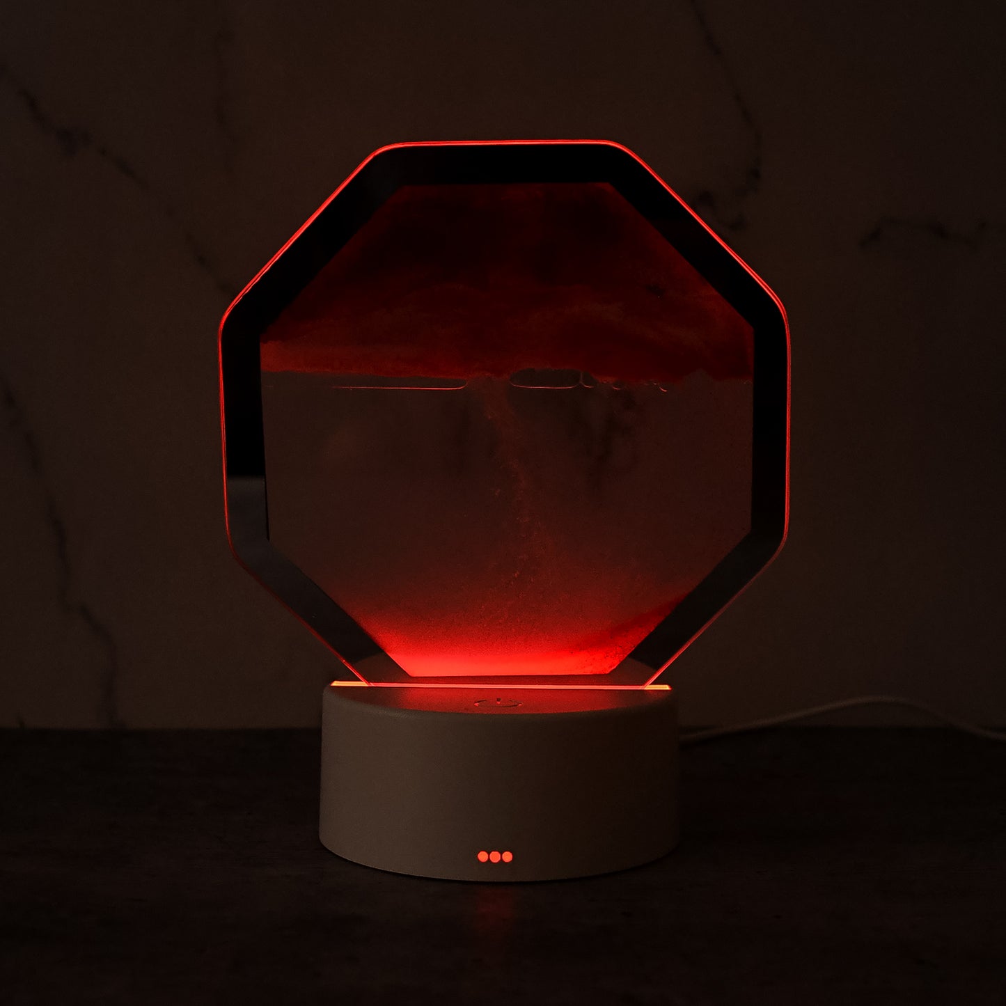 Wukusy LED moving sand art table lamp on office desk, with flowing colorful sand inside a glass container.