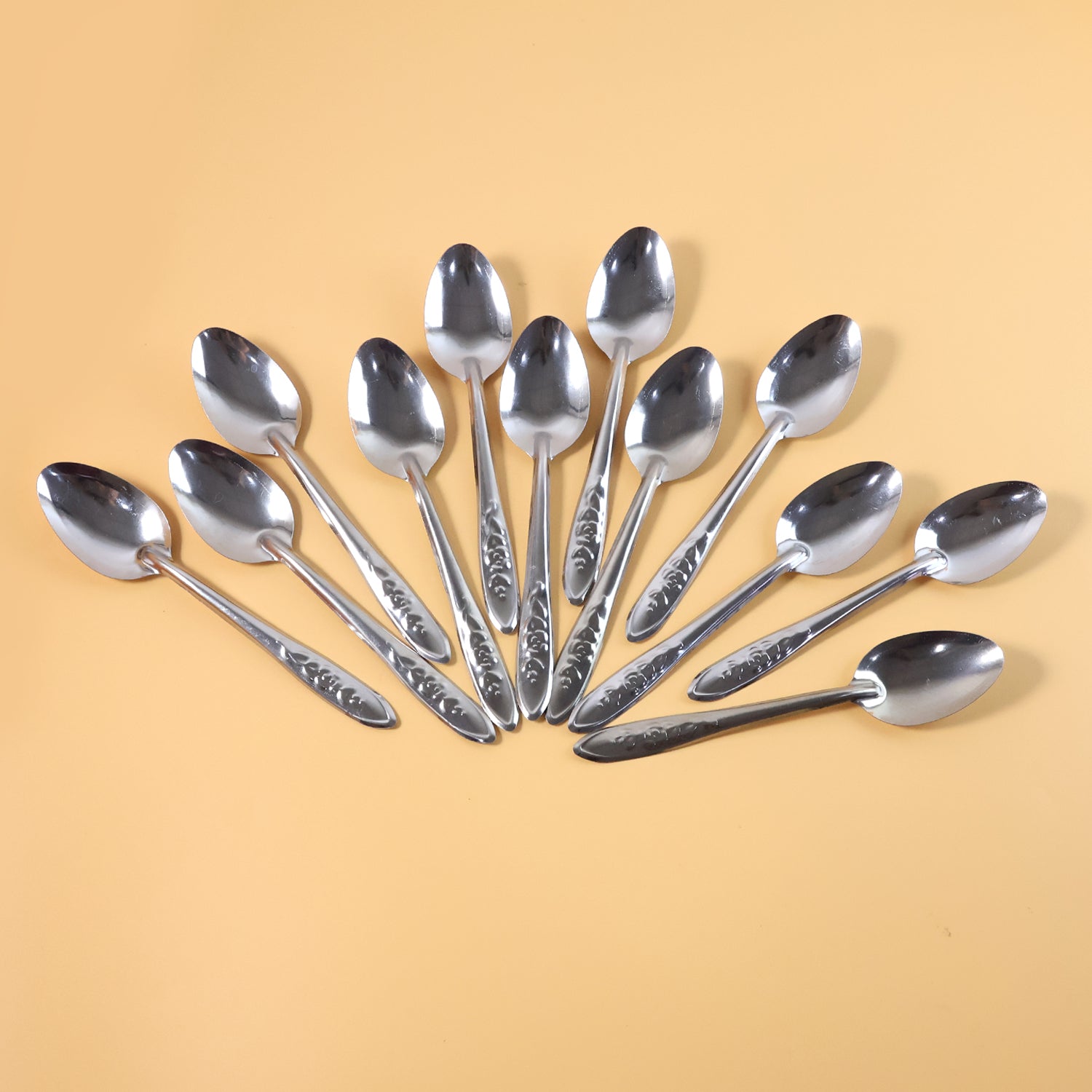 Set of 12 premium stainless steel table spoons by Wukusy, showcasing shiny, polished utensils arranged in a neat pile.