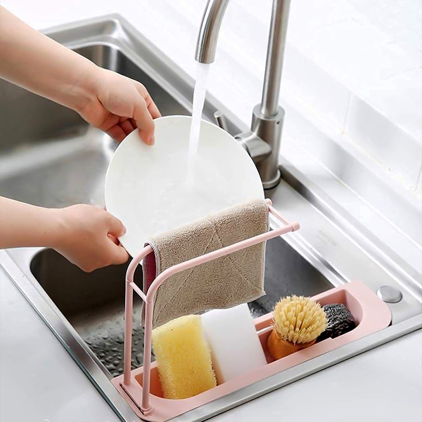 Wukusy over-sink expandable sink caddy with dual towel bar and drip tray, holding dishes and cleaning supplies in a kitchen sink area.