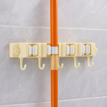 Wukusy self-adhesive wall-mount broom and mop holder rack attached to a wall in a home improvement setting.