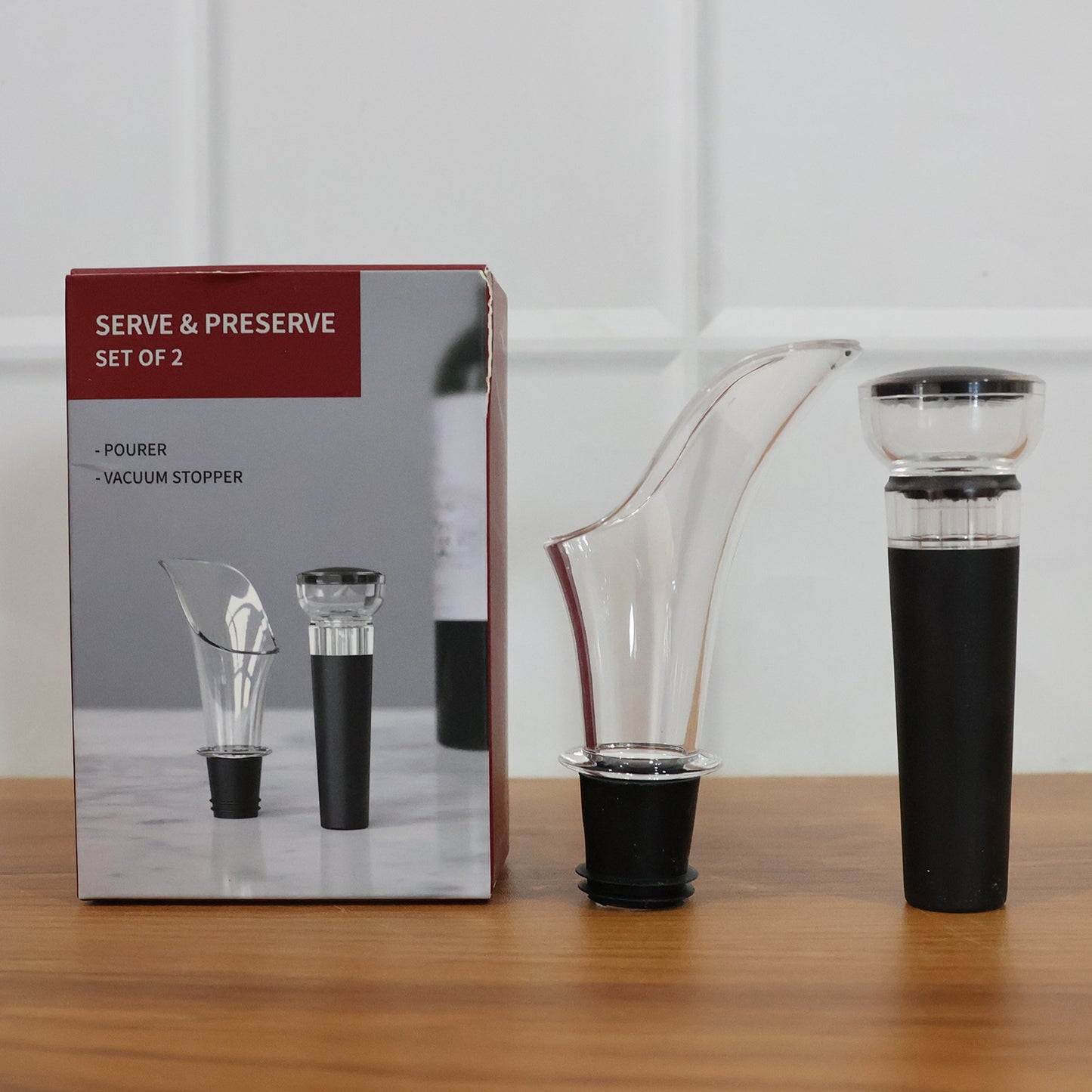 Wukusy premium wine pourer and vacuum bottle stopper set, including two sleek stainless steel wine accessories on a wooden surface.