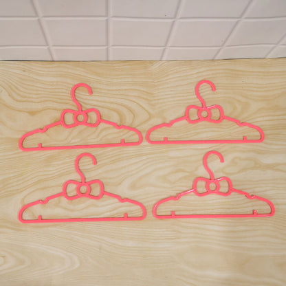 Set of four Wukusy kids plastic clothes hangers with cute bow designs for baby wardrobes, colorful and lightweight.