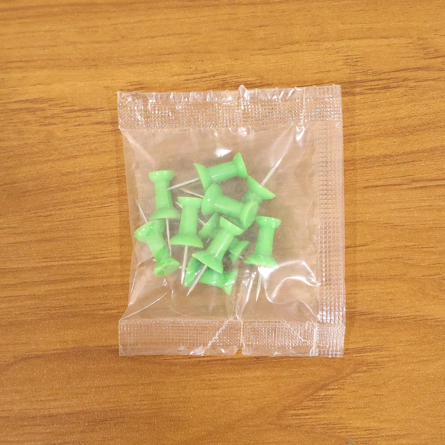 Set of 10 green plastic push pins thumb tacks for notice boards, featuring Wukusy brand, shown on a notice board.