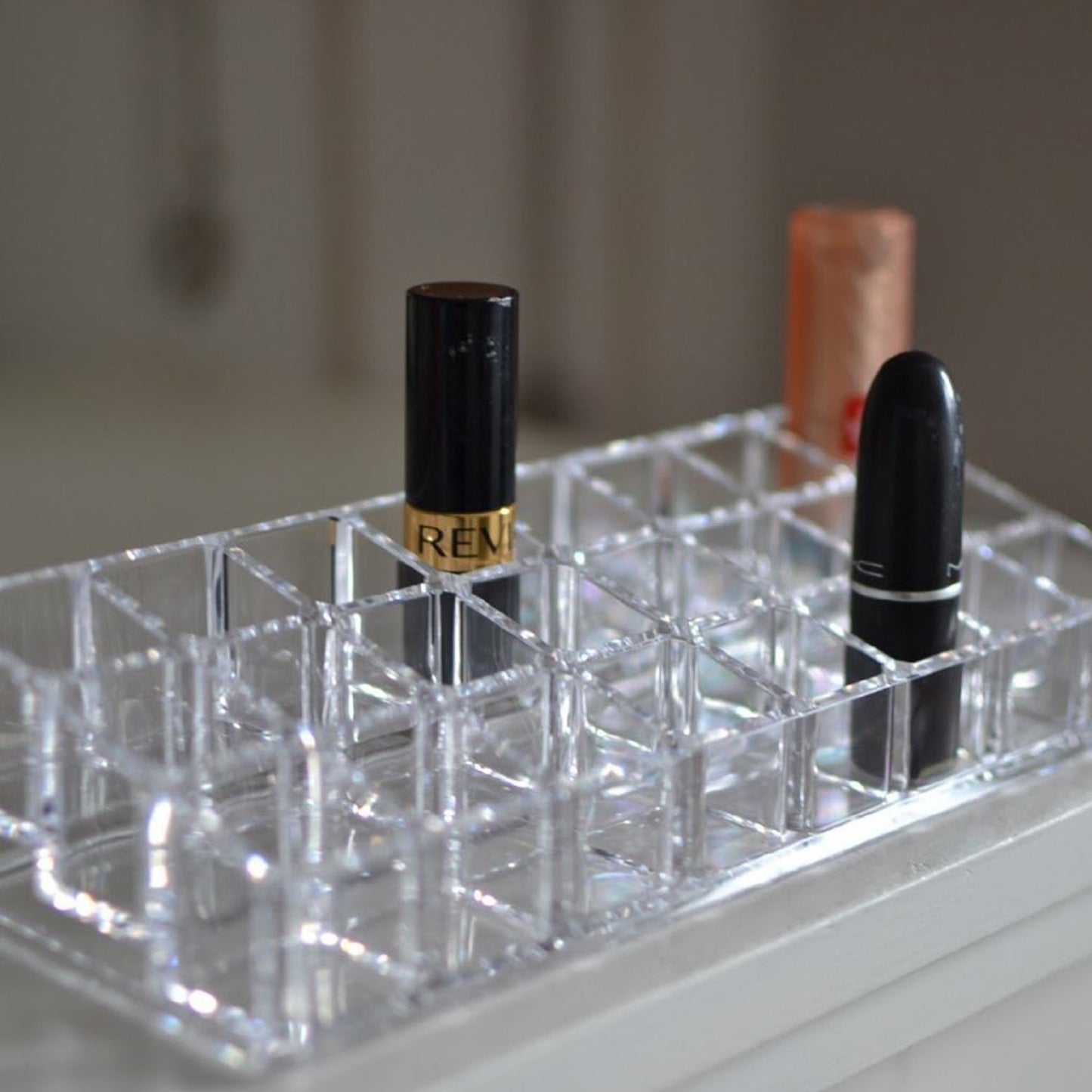 Wukusy acrylic lipstick display stand with 24 sections for organizing makeup and cosmetics in a health and beauty setting.