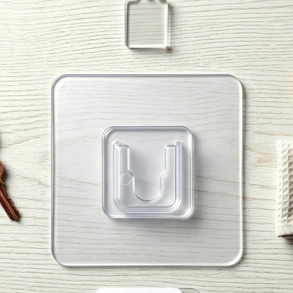 Transparent self-adhesive wall hook by Wukusy mounted on a wall, showing its clear design and adhesive backing.