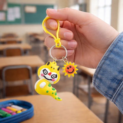 Cute cartoon dinosaur keychain with strap and decorative charm from Wukusy, featuring colorful dinosaur design and playful accessories.