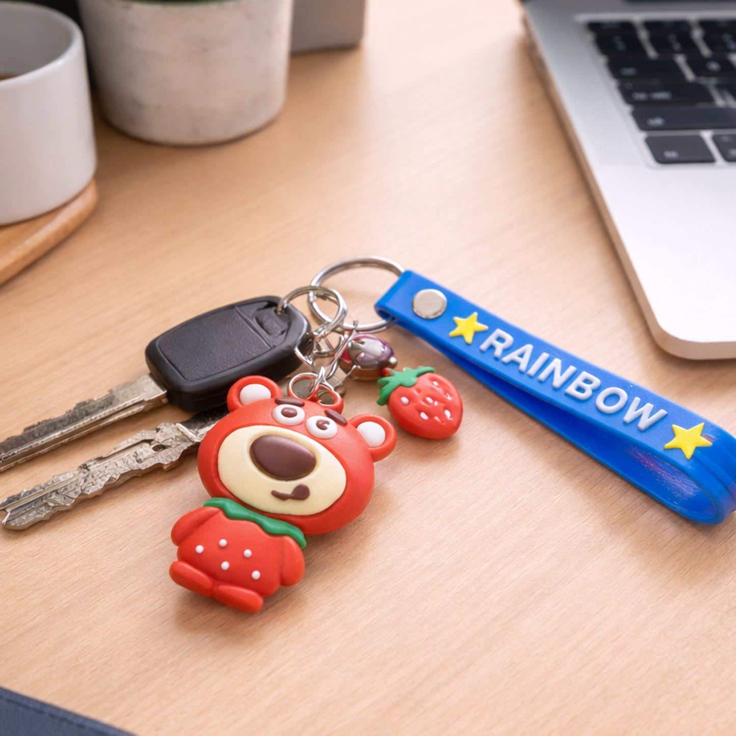 Cute Teddy Bear keychain with rainbow strap from Wukusy, featuring a soft plush teddy bear attached to a colorful strap.