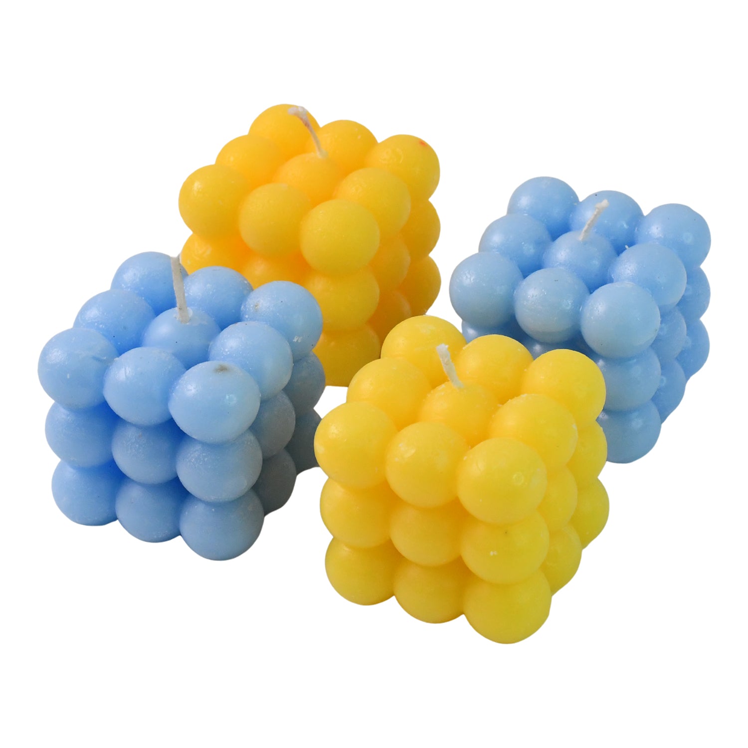 Four colorful cube-shaped wax candles arranged on a neutral surface, showcasing vibrant hues and geometric design.