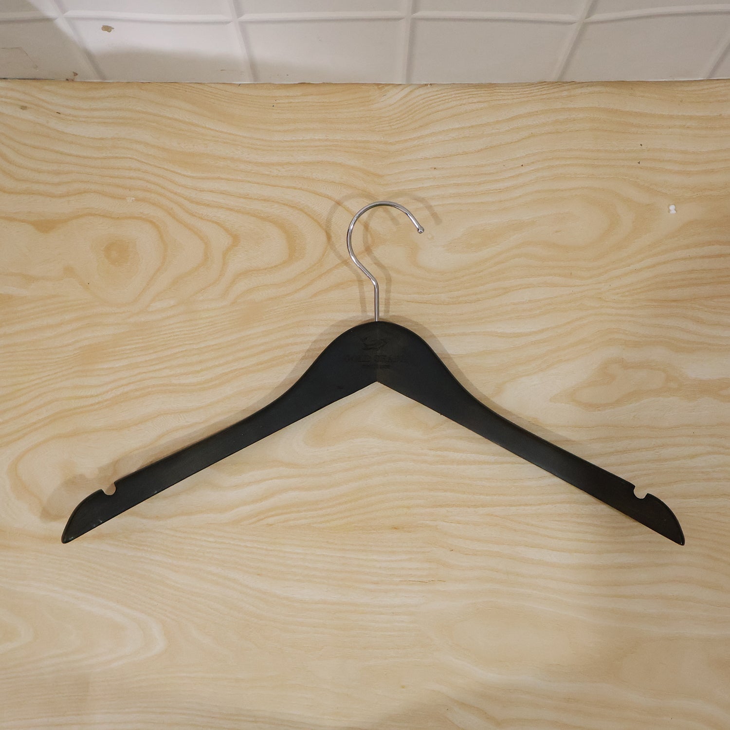 Wukusy premium cloth hanger with metal hook for shirts, coats, and tops, displayed hanging in a wardrobe.