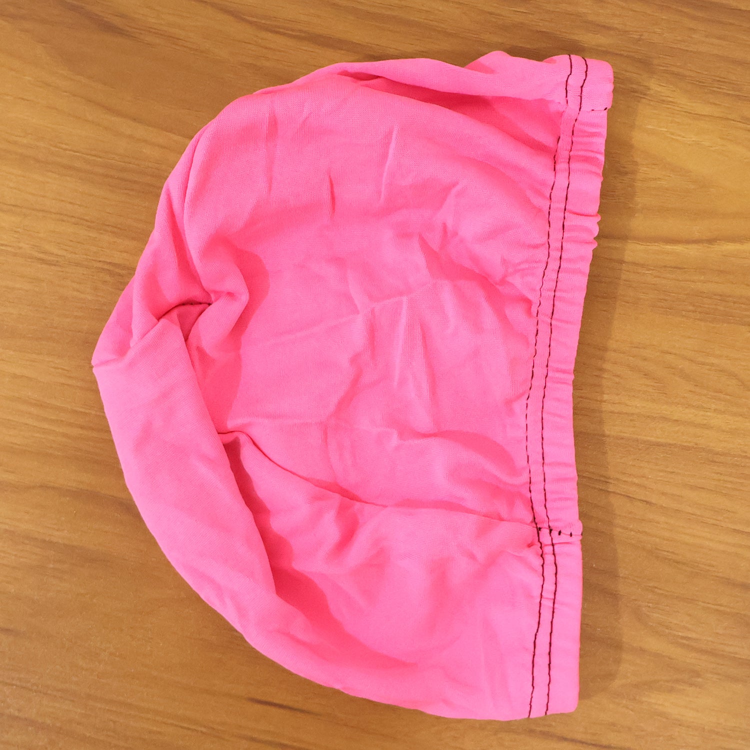 Wukusy small premium stretchable swimming cap in black, shown on a model's head, designed for comfortable water sports use.