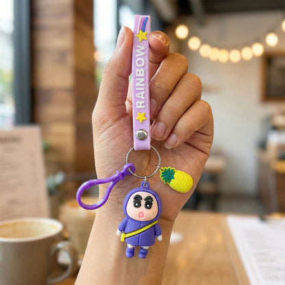 Cute cartoon doll keychain by Wukusy with strap and pineapple charm, featuring colorful, playful design, ideal for bags and keys.