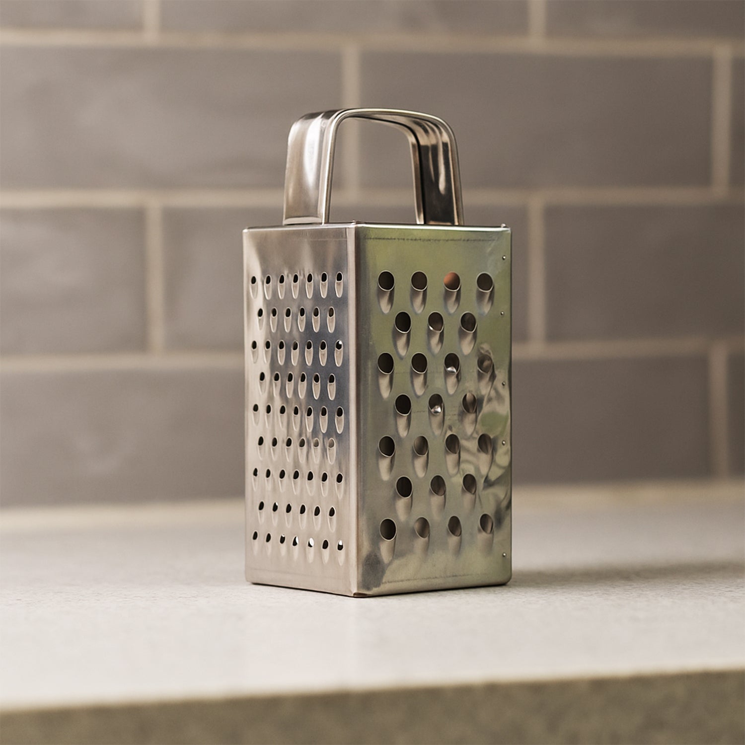 Wukusy Supermom Premium 4-in-1 stainless steel grater and slicer for kitchen use, compact design with multiple grating and slicing options.