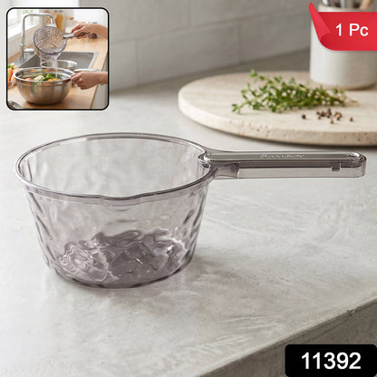 Transparent plastic water dipper scoop with handle for bathroom use, designed by Wukusy, shown with water in a bathroom setting.