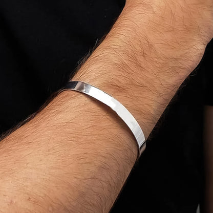 Minimalist polished silver-tone stainless steel kada bracelet by Wukusy, open-ended fashion jewelry on a white background.