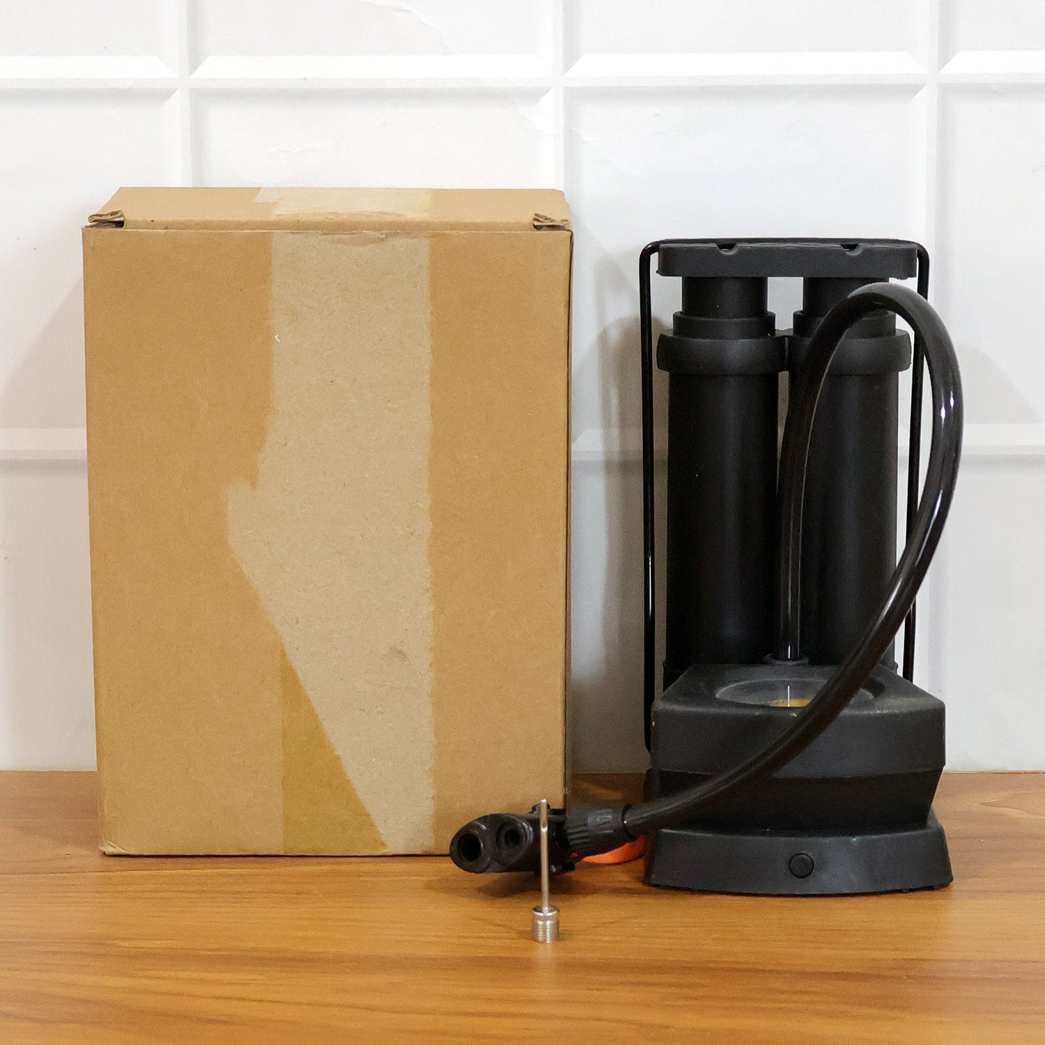 Wukusy double cylinder foot air pump with two nozzles for inflating tires, sports balls, and inflatable items, shown in use.