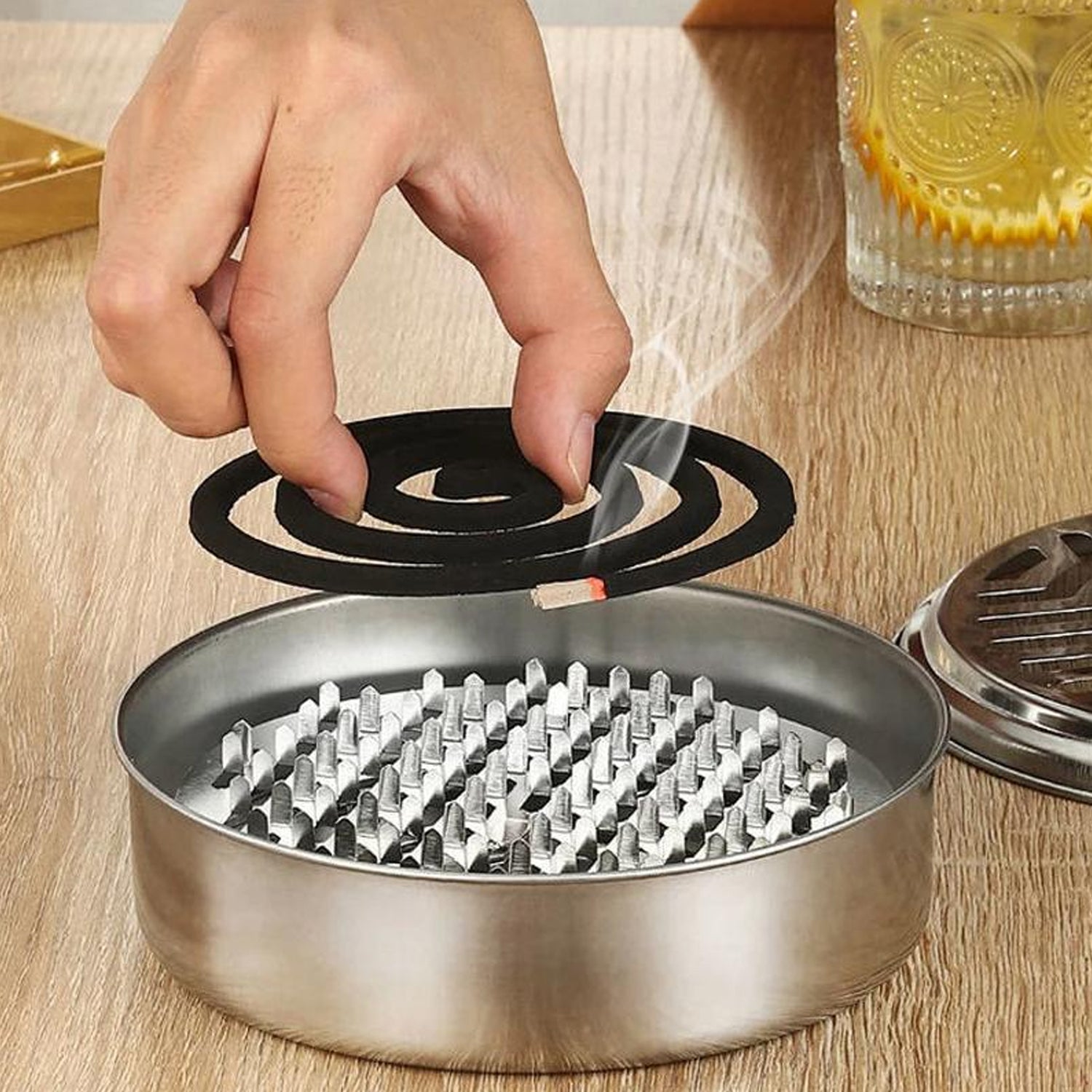 Stainless steel mosquito coil stand with smoke vent lid by Wukusy, designed to hold mosquito coils securely and improve airflow.