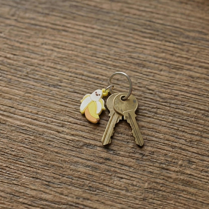 Set of 10 cute cartoon banana bag charm keychains from Wukusy, featuring colorful, playful banana designs on keychains.