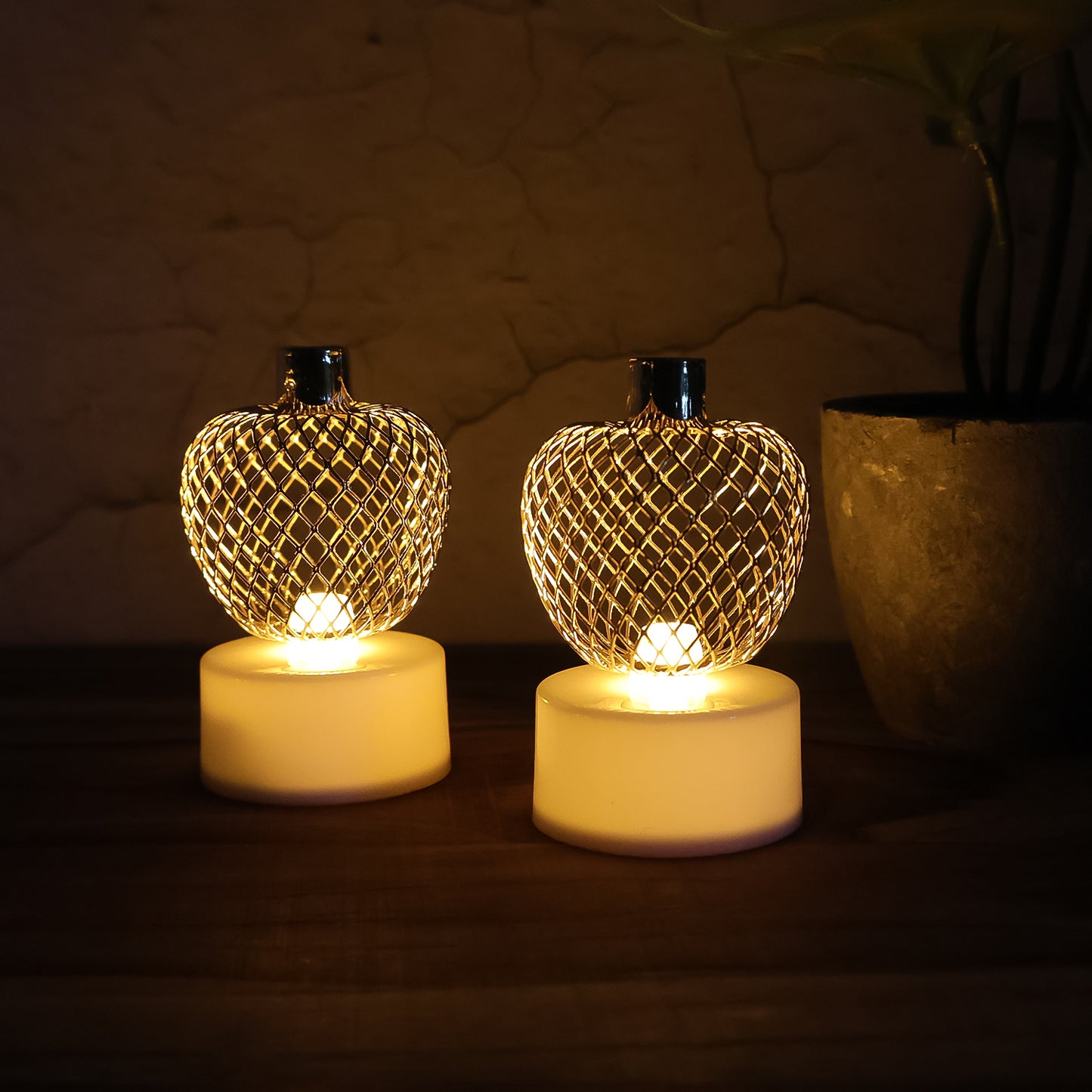 Set of four decorative apple-shaped LED tealight candles by Wukusy for home decor, glowing softly in warm light.