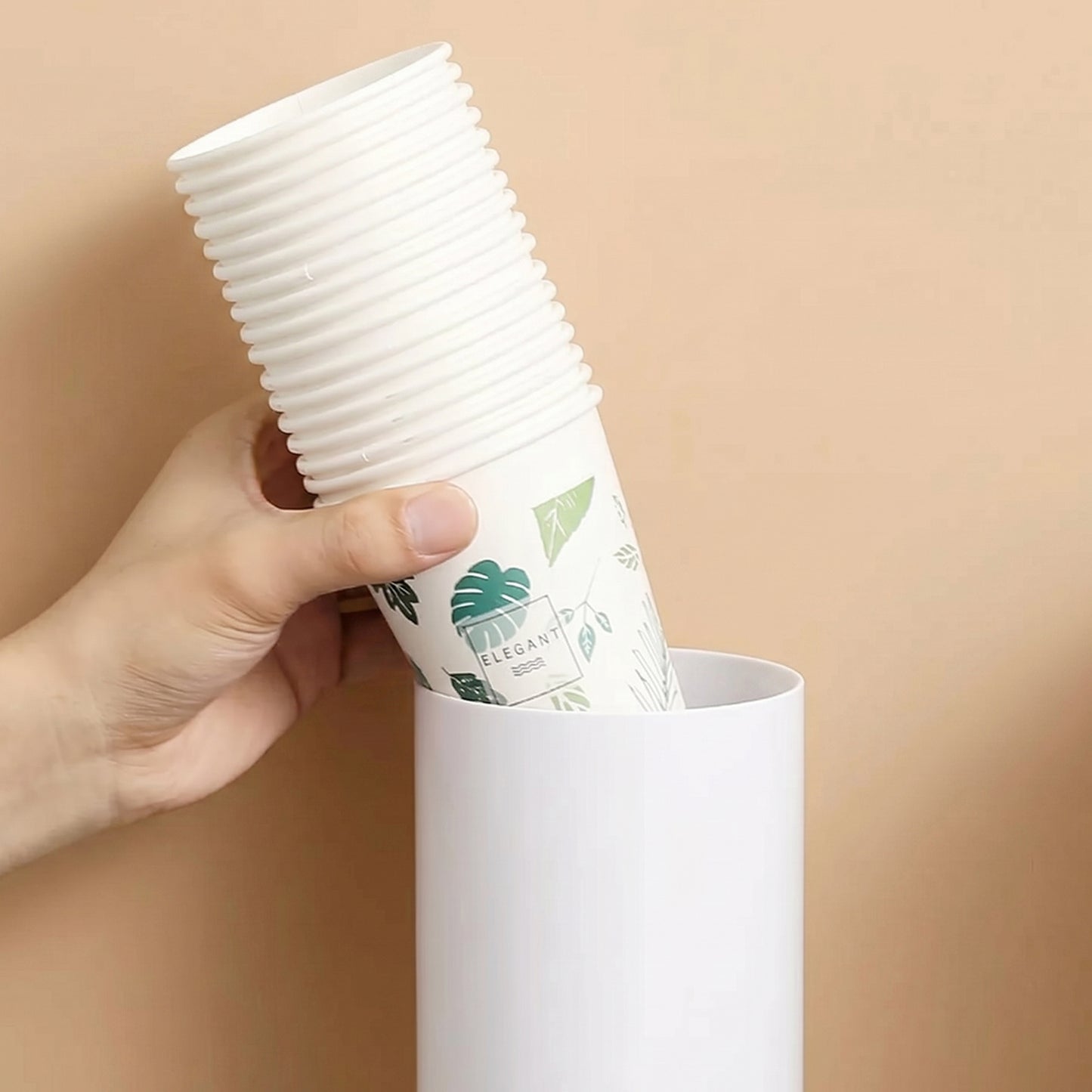 Wall-mounted Wukusy paper cup holder dispenser for disposable cups, mounted on a wall, with visible cups stored inside.