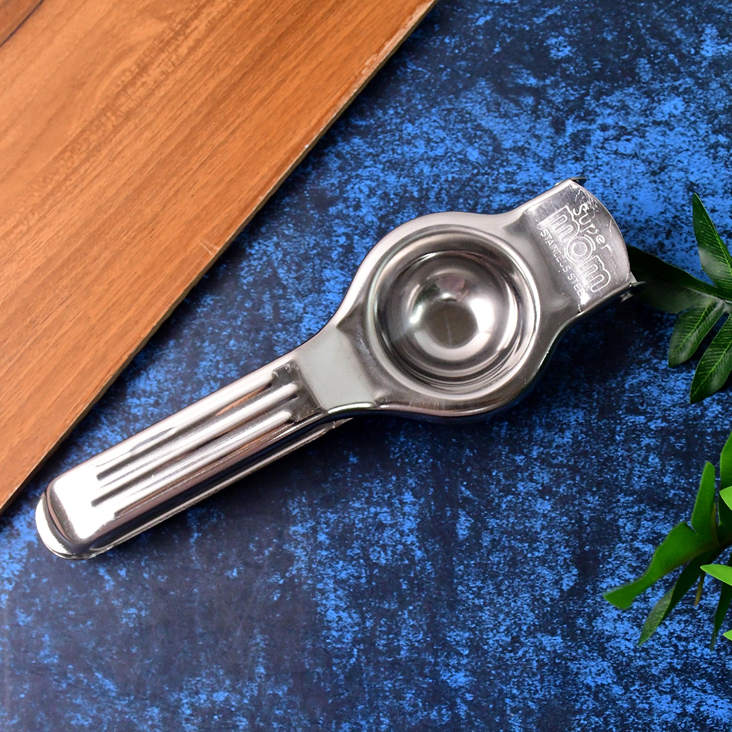 Wukusy Supermom 2-in-1 stainless steel lemon squeezer with built-in bottle opener in a home kitchen setting.