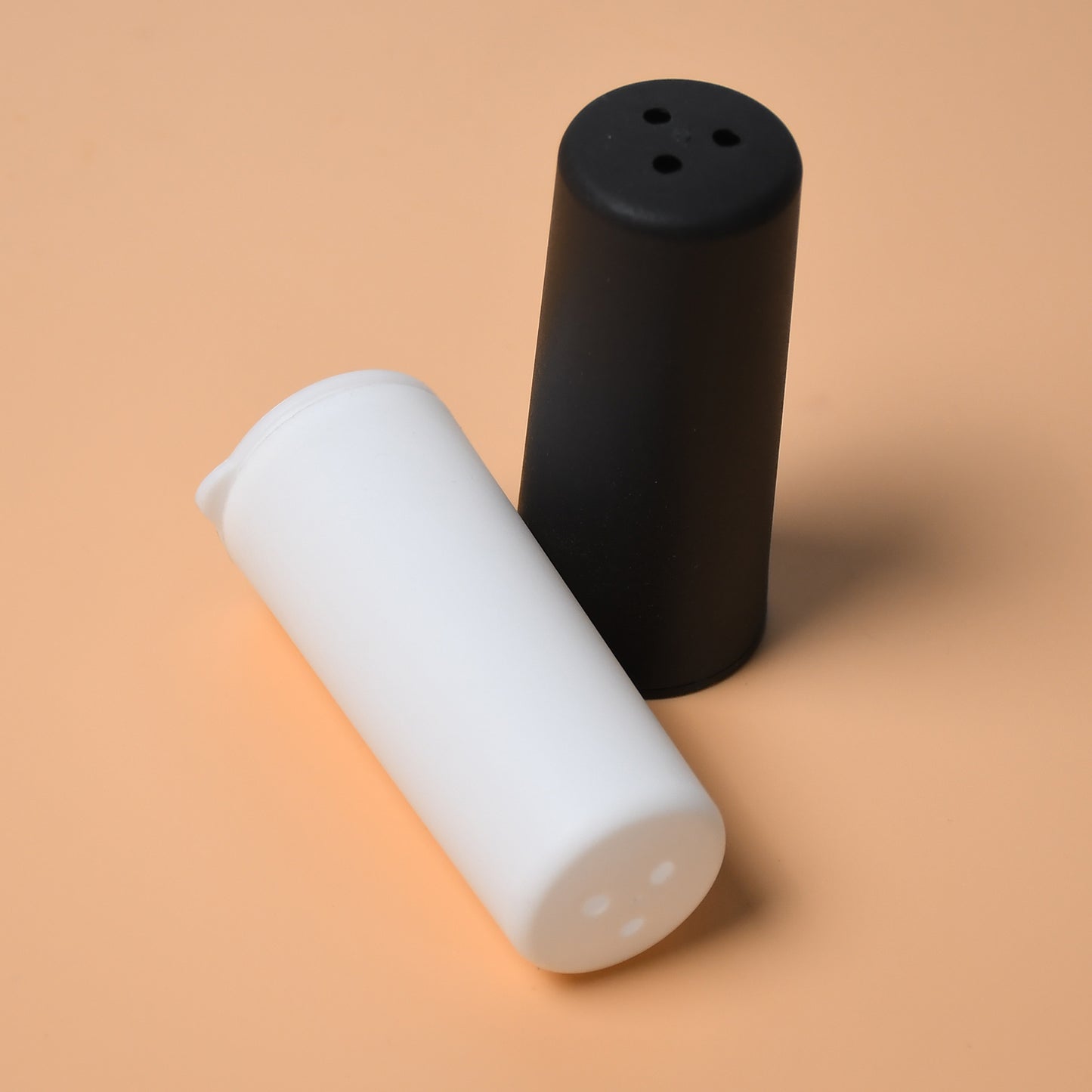 Wukusy 5317 salt and pepper dispenser set on a dining table, perfect for home or hotel spice storage and seasoning.
