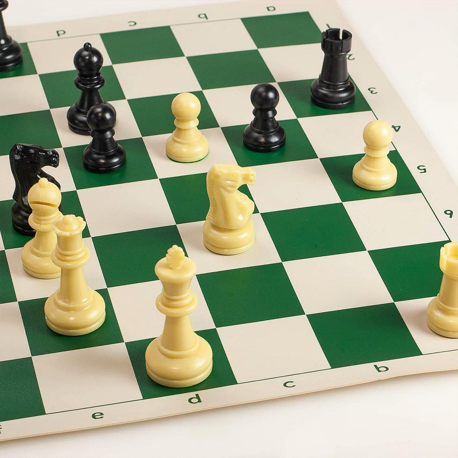 Small Wukusy plastic portable chess set with black and white chess pieces arranged on a playing surface.