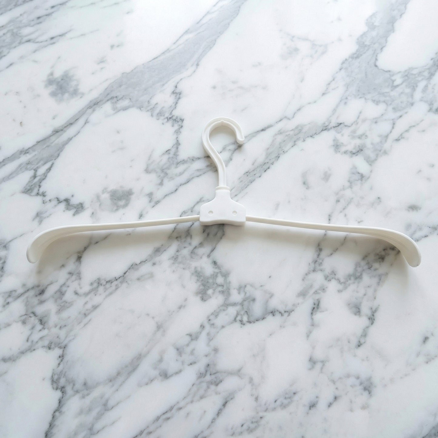 Wukusy premium foldable plastic clothes hanger hanging on a closet rod, compact and sturdy for versatile clothing organization