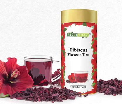 Freshville Hibiscus Tea in a glass teapot, showcasing vibrant red hibiscus flowers and brewed tea with fresh leaves.