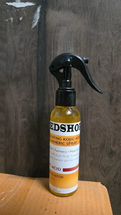 Two 400 ml bottles of 18058 Exfoliating Kojic Acid Turmeric Spray, clear plastic bottles with spray nozzles and turmeric branding.
