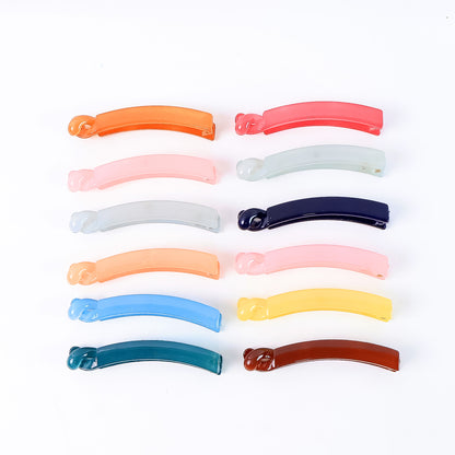 Set of 12 multicolor plastic banana-shaped hair clips by Wukusy, arranged on a white background.
