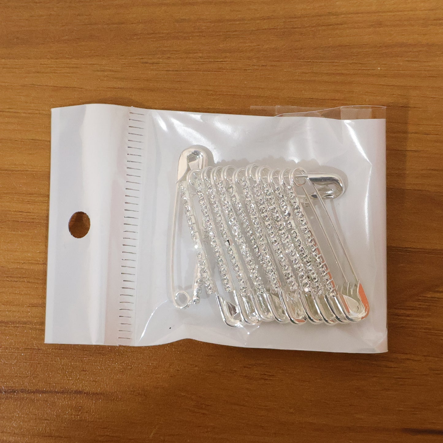 Set of 12 decorative silver finish safety pin brooches by Wukusy, featuring shiny metallic accents for stylish accessories.