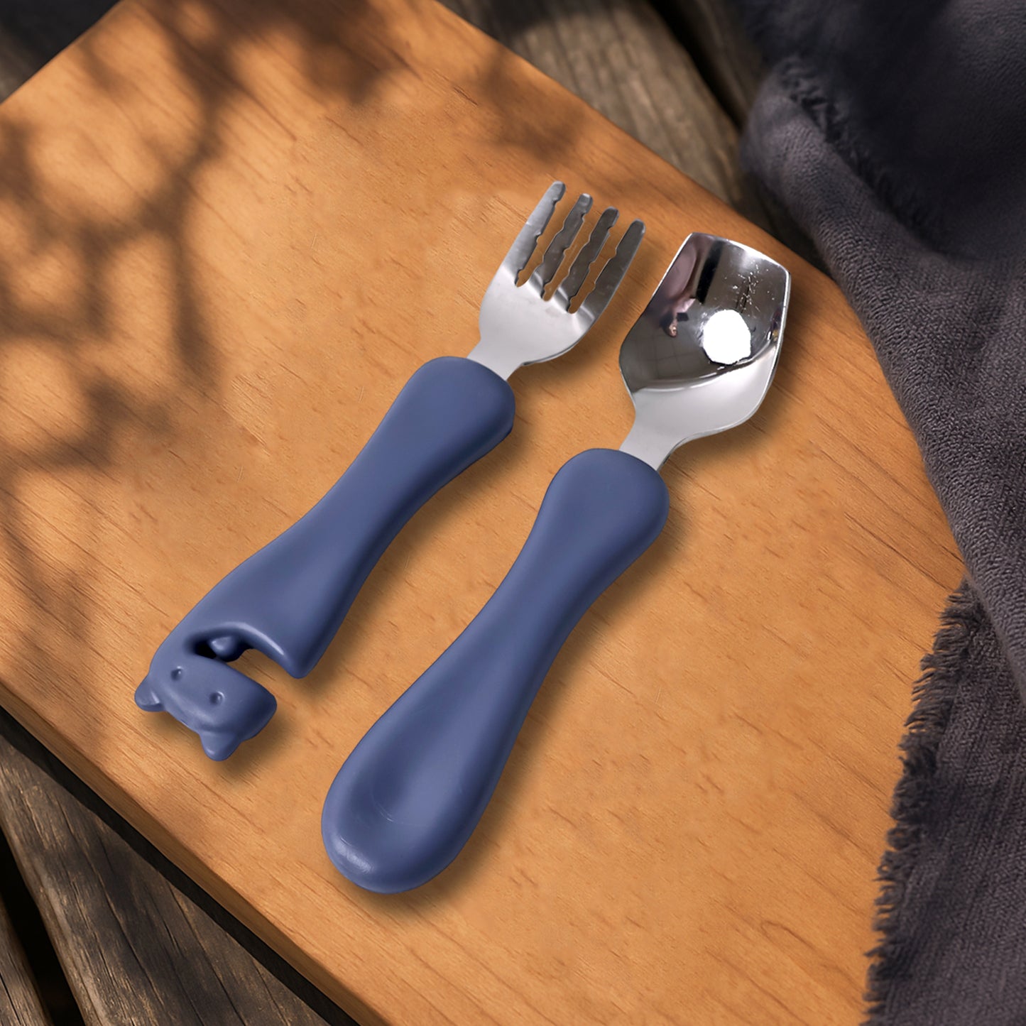Wukusy Supermom Foodie stainless steel spoon and fork set for home use, shiny metallic utensils on a clean kitchen background.