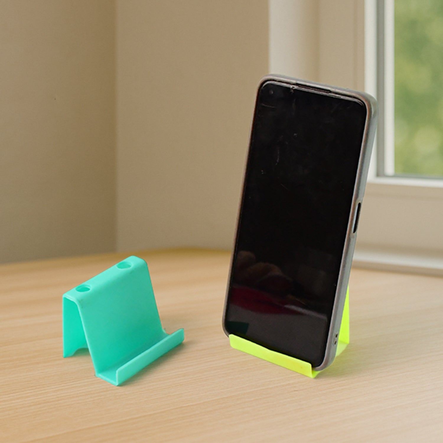 Two Wukusy multifunctional plastic mobile phone stands and pen holders in mixed colors, featuring adjustable support and storage compartments.