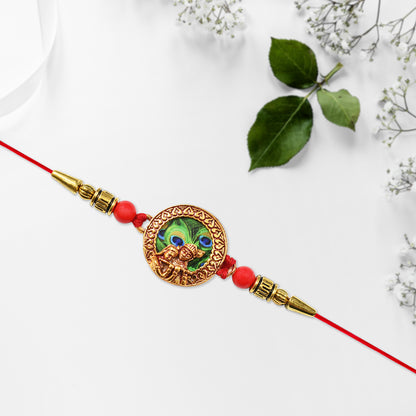 Traditional Krishna Rakhi with peacock feather design, decorative beads, on red thread, by Wukusy, for festive Raksha Bandhan celebrations.