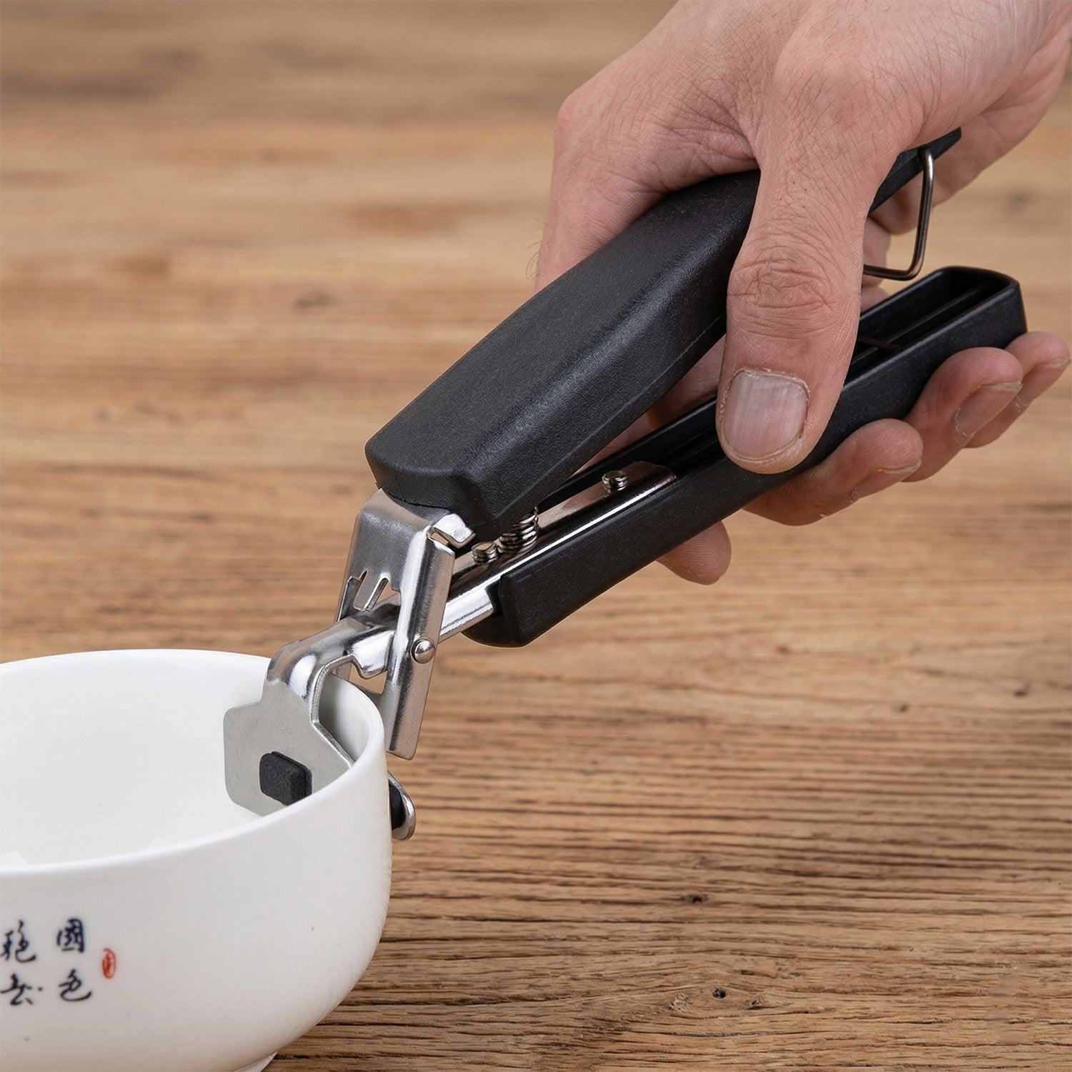 Wukusy heavy-duty universal pot and pan gripper clamp for secure handling of cookware, shown in a close-up image.
