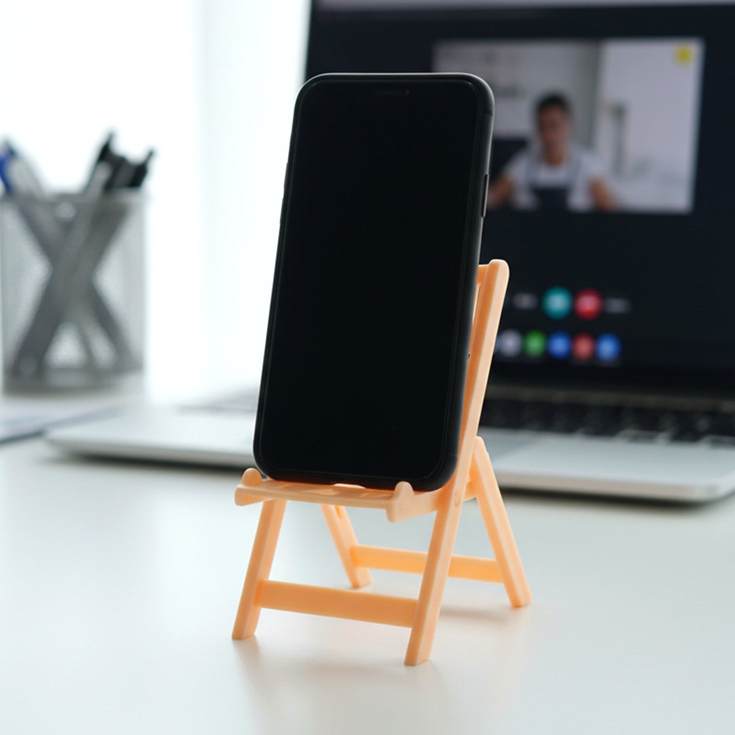 Peach-colored Wukusy mini chair shape mobile stand holder on a white background, showcasing its cute, compact design.