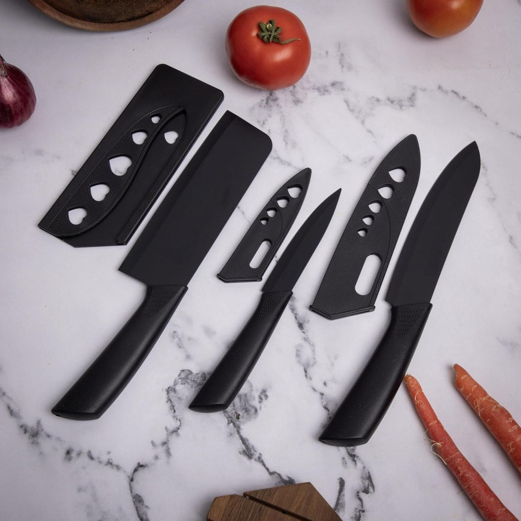 Three stainless steel knives in a FIZZI SHOP JK SIDHU 3-piece knife set displayed on a wooden cutting board.
