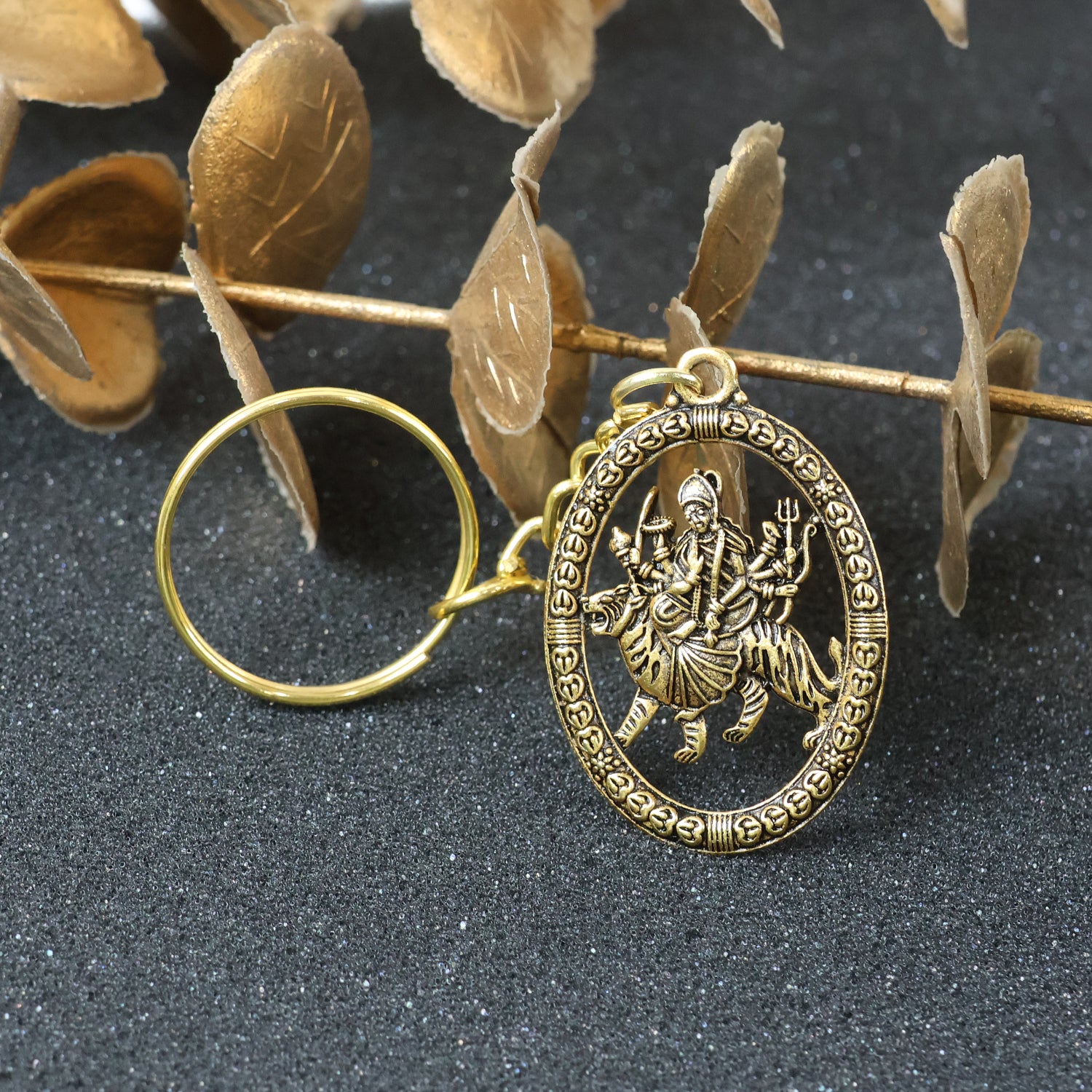 Golden Maa Durga oval frame keychain with intricate design, featuring a religious goddess figure, attached to a keyring.