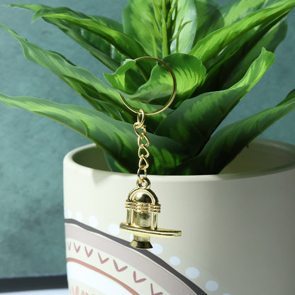 Golden metal Shivling keychain with intricate design, attached to a keyring, by Wukusy.