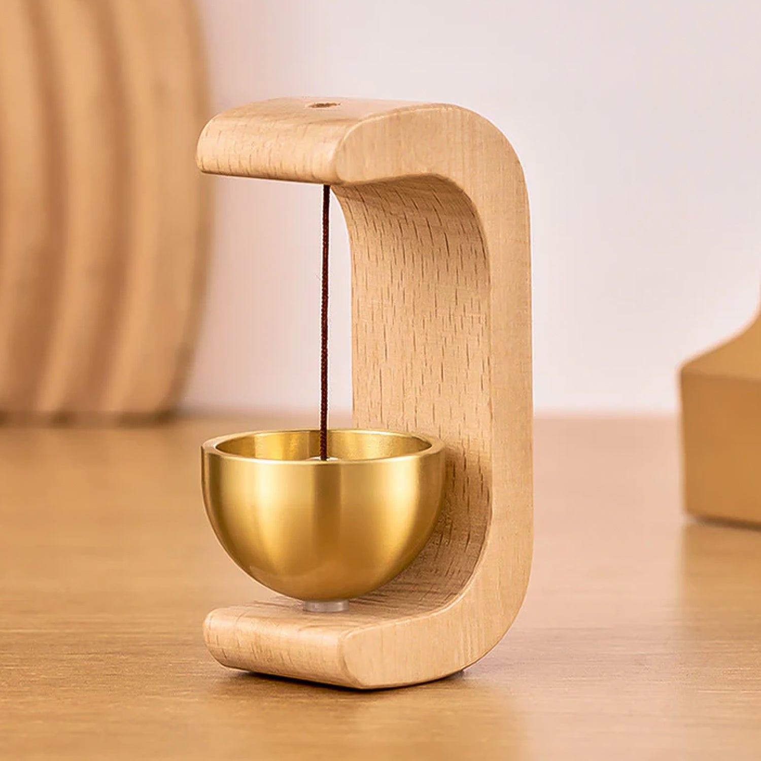 Wukusy premium desktop Japanese-style Zen bell with a wooden handle and intricate metal design, placed on a wooden surface.