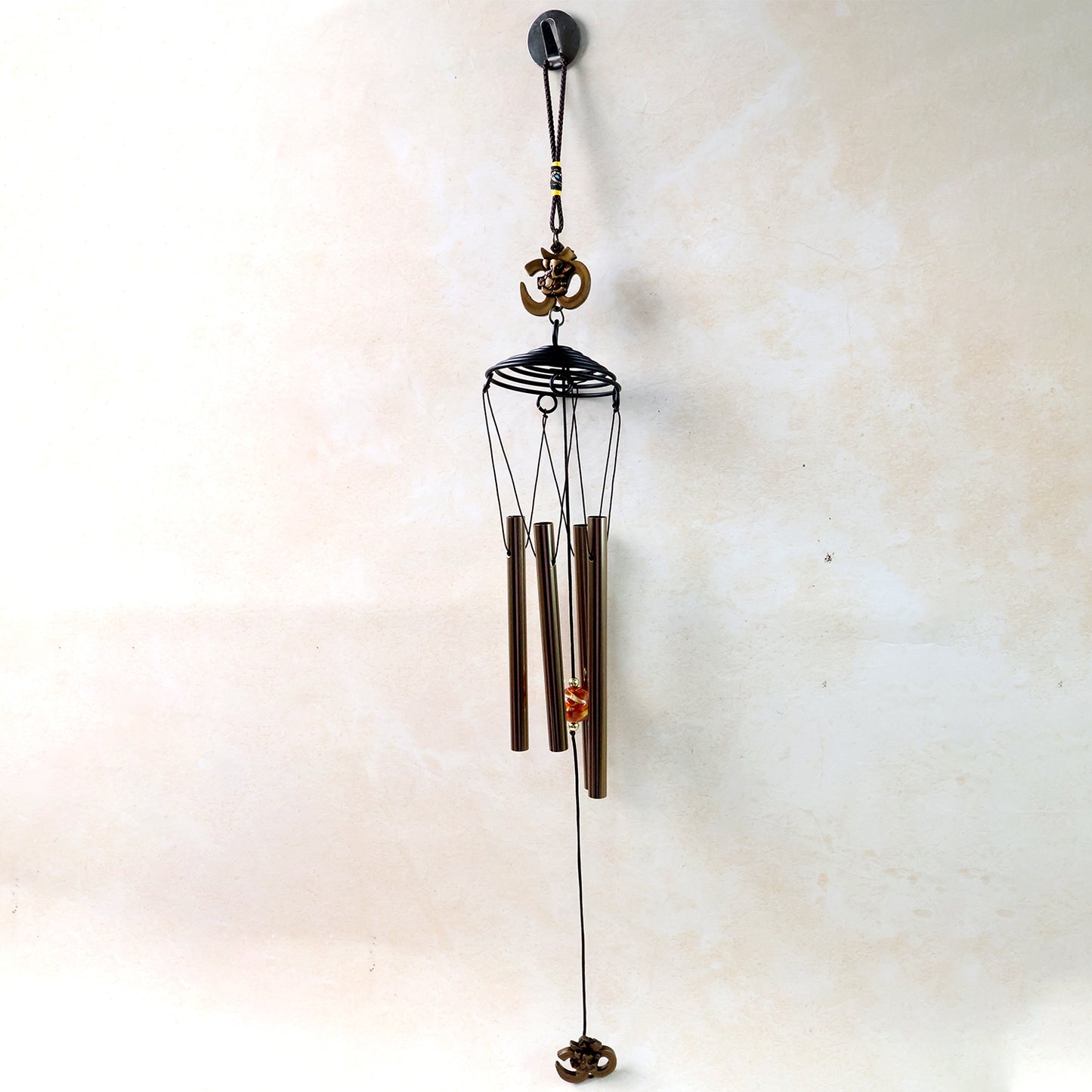 Metal wind chime with Om symbol, Wukusy brand, featuring hanging tubes and decorative Om design for outdoor or indoor use.