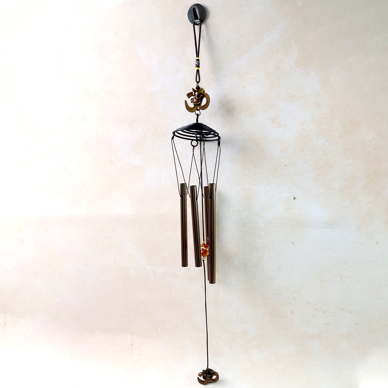 Metal wind chime with Om symbol, Wukusy brand, featuring hanging tubes and decorative Om design for outdoor or indoor use.