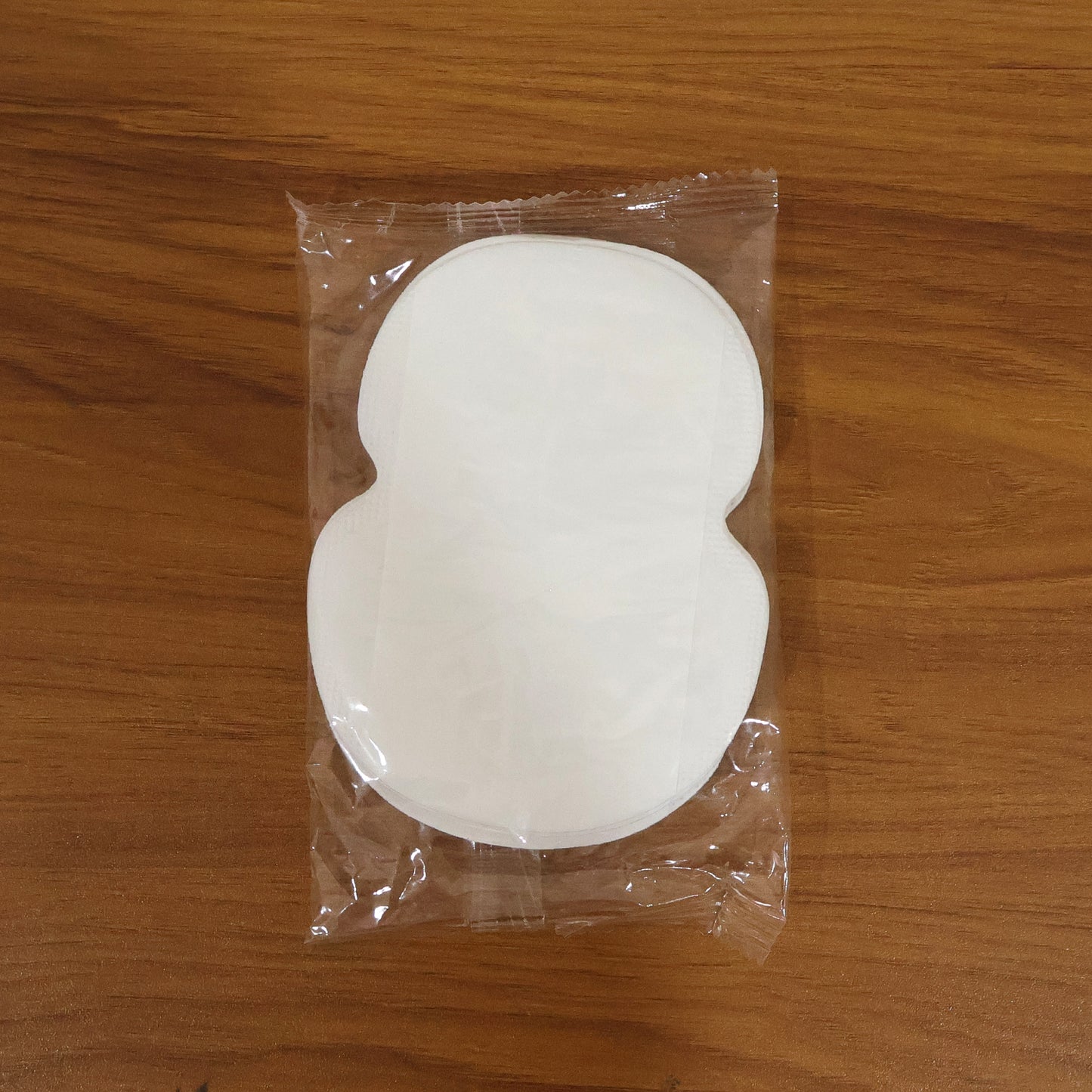 Wukusy underarm sweat pads, 10-piece pack, shown in a close-up with the pads ready for use on clothing or skin.