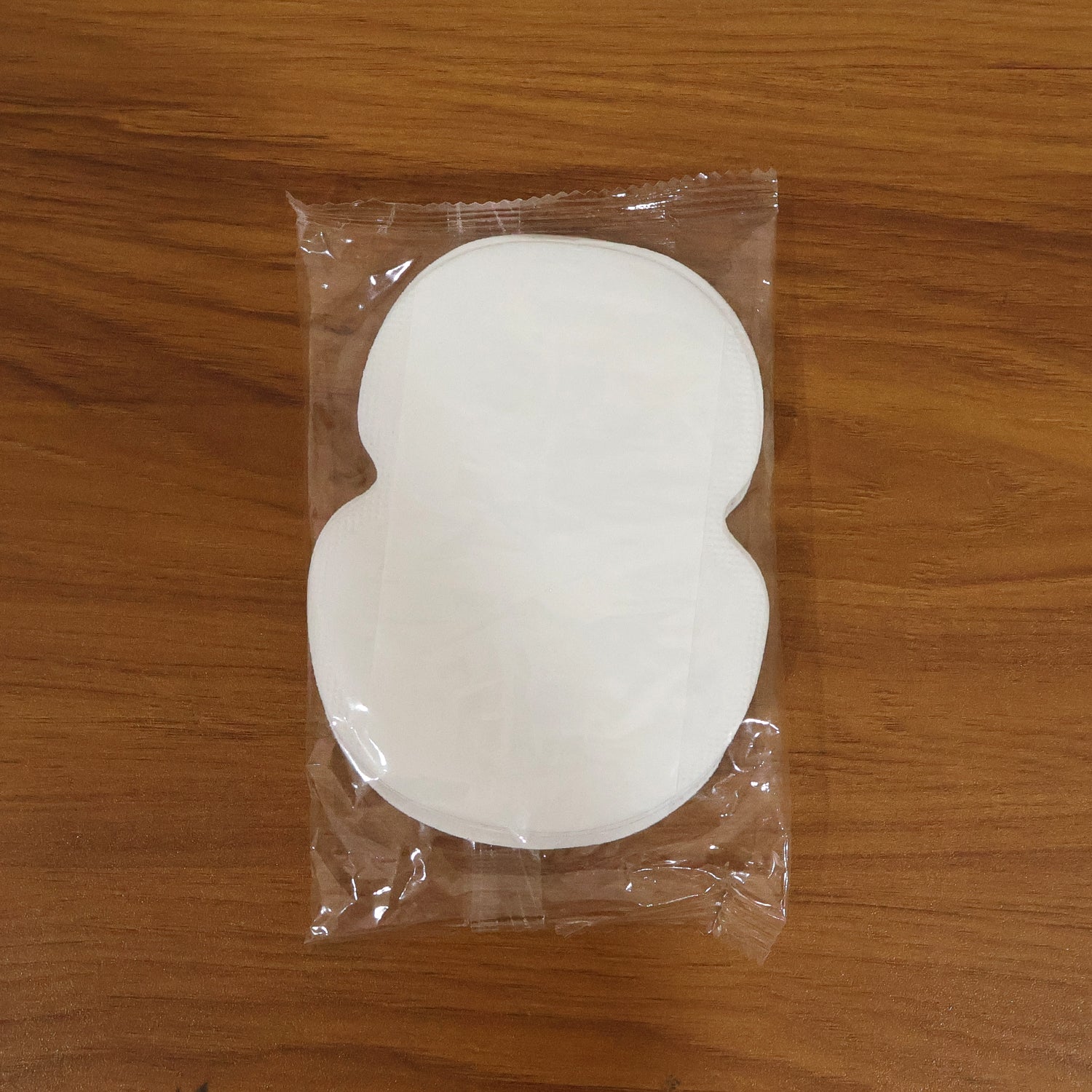 Wukusy underarm sweat pads, 10-piece pack, shown in a close-up with the pads ready for use on clothing or skin.