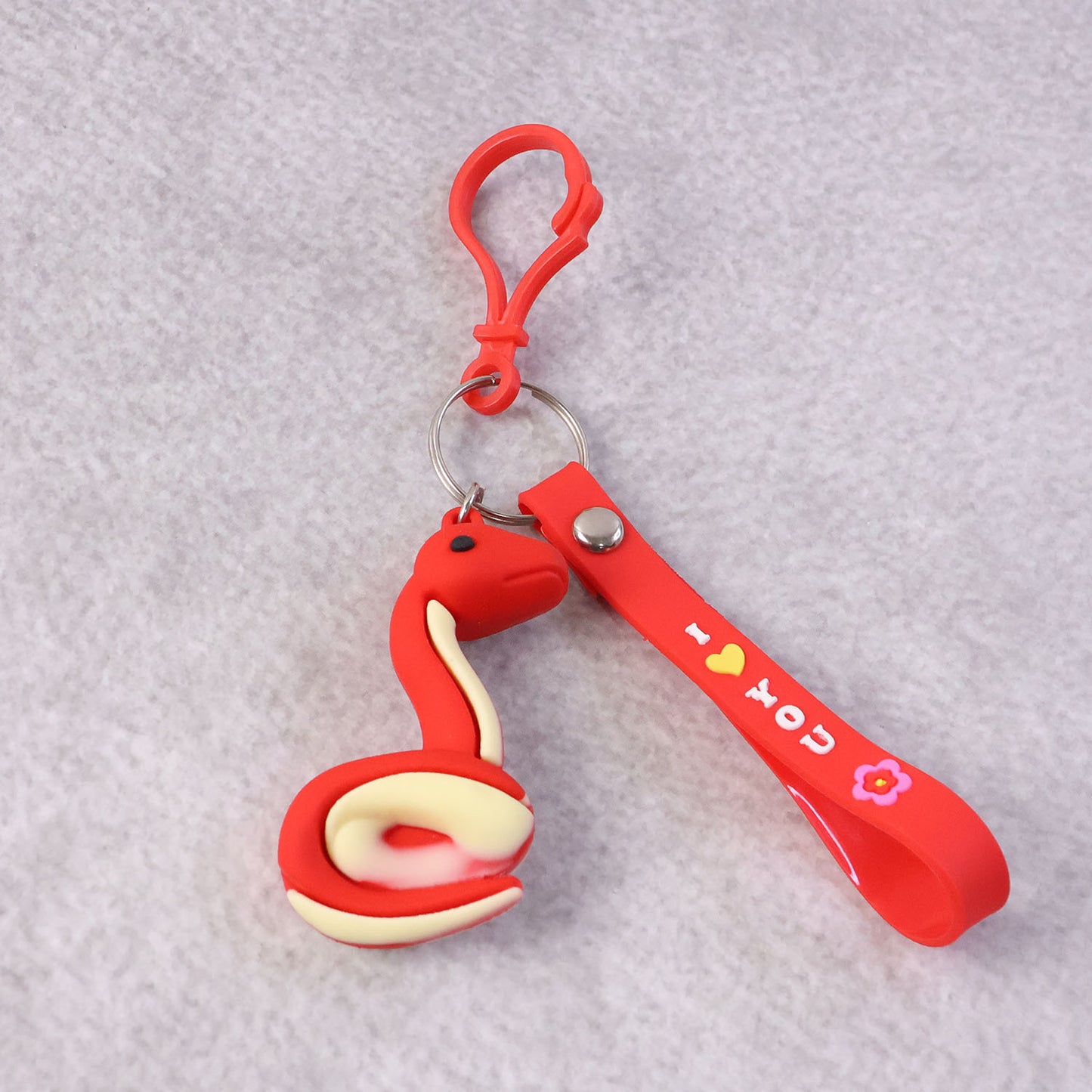 Cute cartoon snake keychain by Wukusy featuring a colorful, smiling snake design on a small metal keyring.