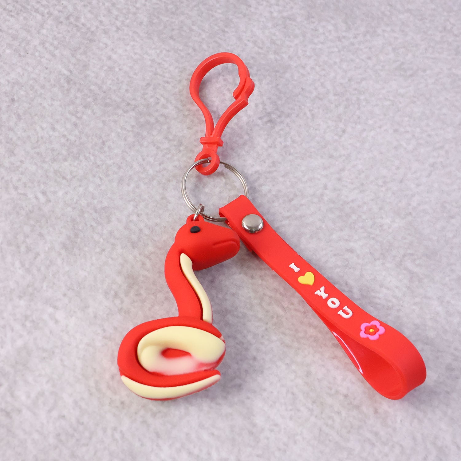 Cute cartoon snake keychain by Wukusy featuring a colorful, smiling snake design on a small metal keyring.