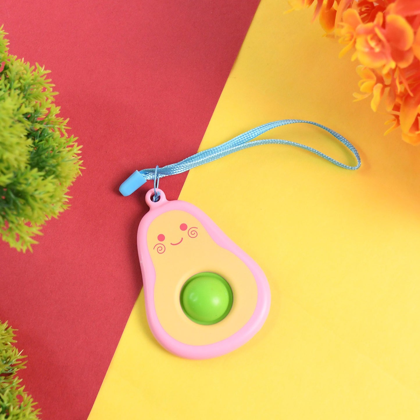 Cute avocado-shaped mini push pop keychain toy with strap, colorful and fun accessory by Wukusy.