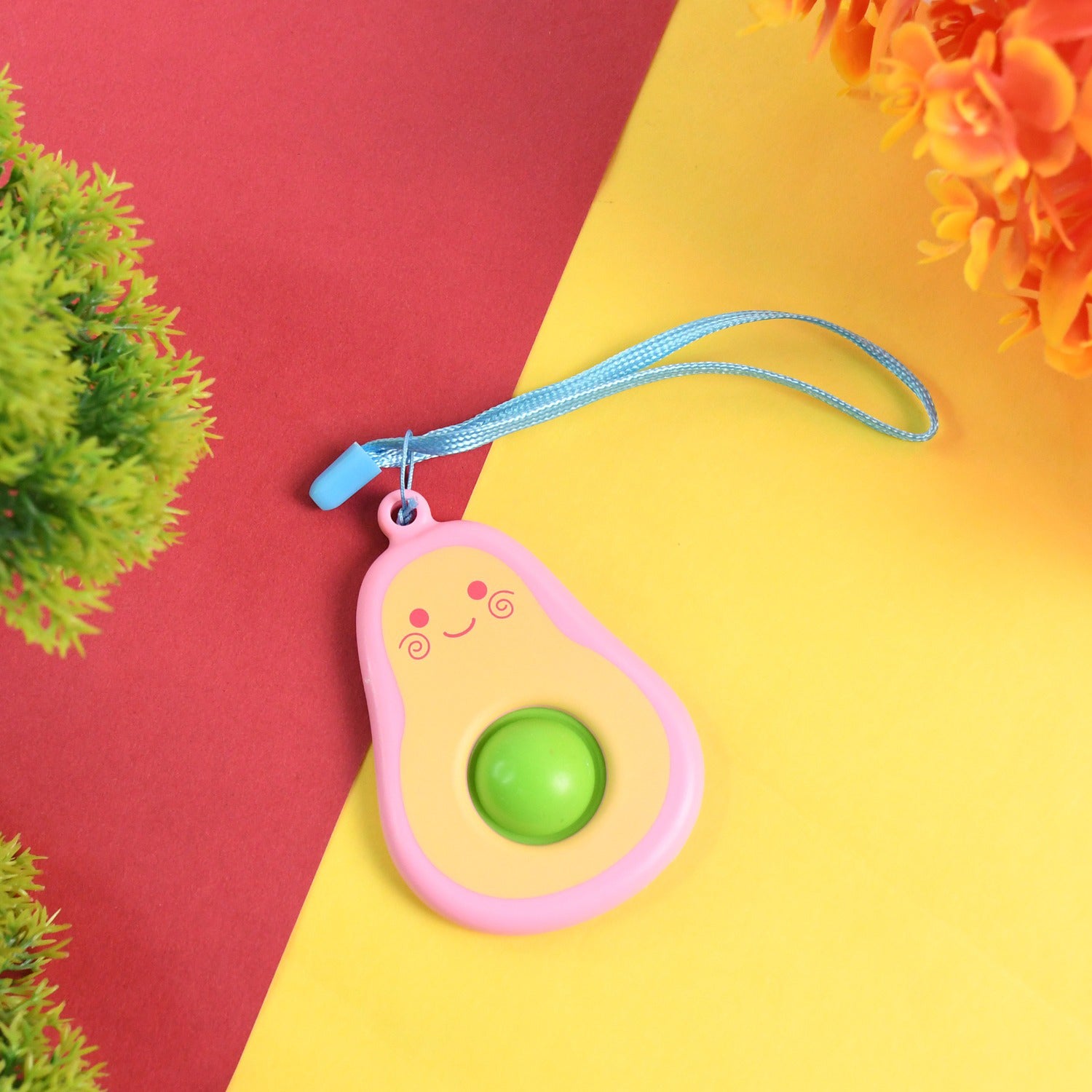 Cute avocado-shaped mini push pop keychain toy with strap, colorful and fun accessory by Wukusy.