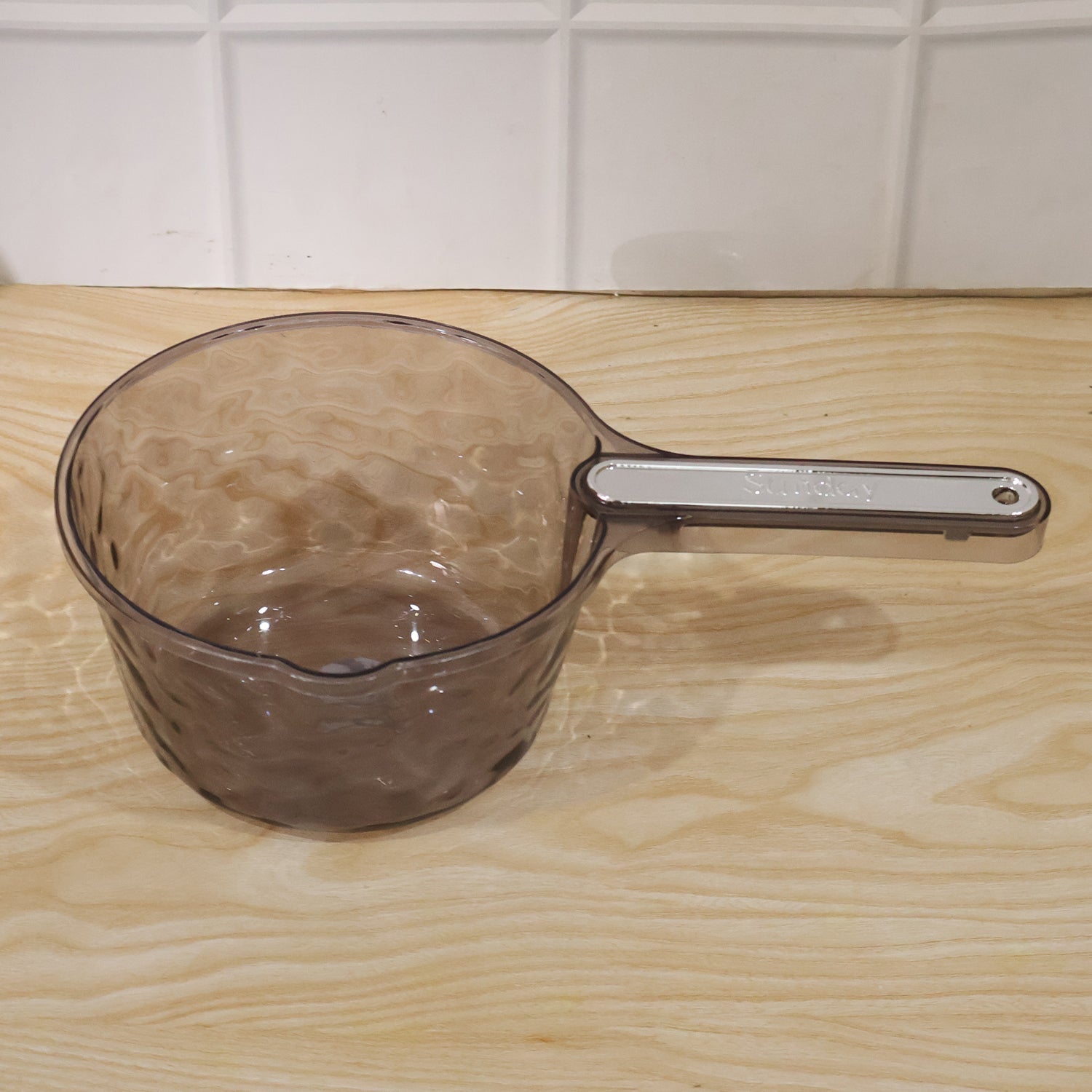 Wukusy transparent plastic water dipper scoop with handle, designed for bathroom use, shown with water inside the scoop.