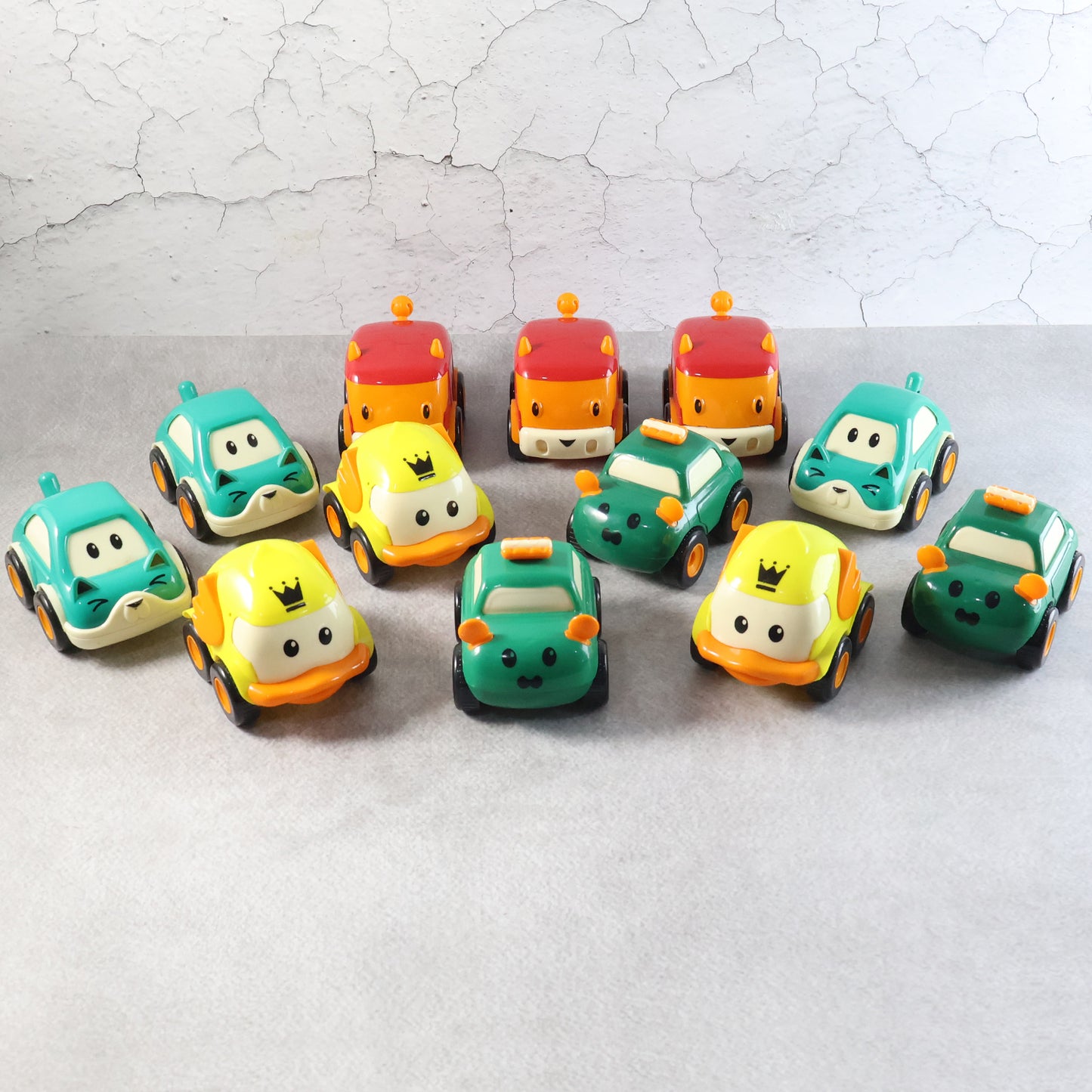 Set of 12 Wukusy cartoon pull-back toy cars for kids, colorful plastic cars with animated designs on a white background.